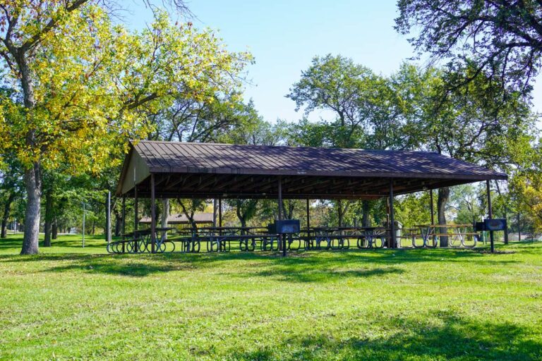 a picnic shelter in a park with grills nearby