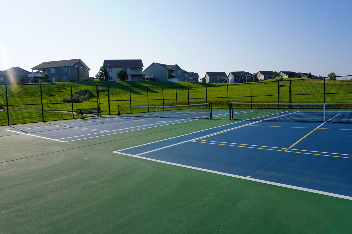 two pickleball courts at Johnny Gisi Memorial Park with houses on top of a hill in the background