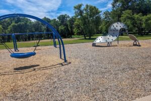 blue playground at Pioneer Park with swing, tire swing, and climbing structure