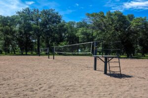 two sand volleyball courts with nets and a stand for the official