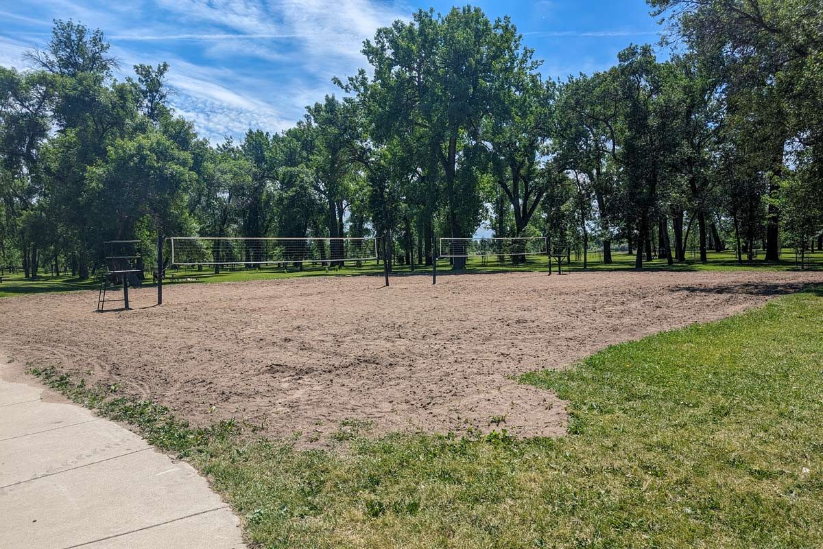 two sand volleyball courts at Pioneer Park with tall trees surrounding them