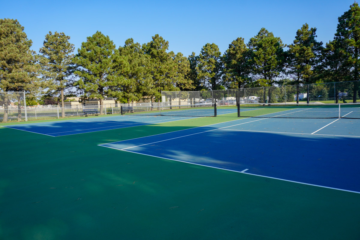 two tennis courts at Sons of Norway Park surrounded by tall trees