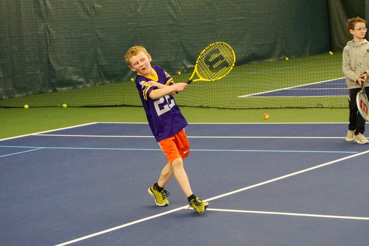 boy swings tennis racquet during tennis at CRFC