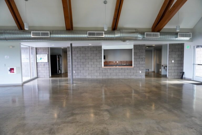 wide angle view of the interior of an indoor community center with a window to a kitchenette