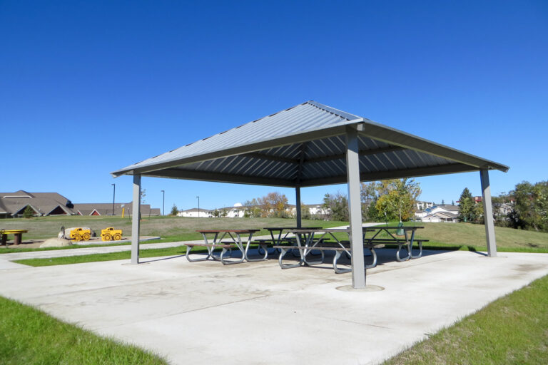 outdoor shelter with picnic tables near a playground