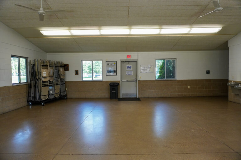 wide angle view of the interior of an indoor community shelter with chairs and a water fountain